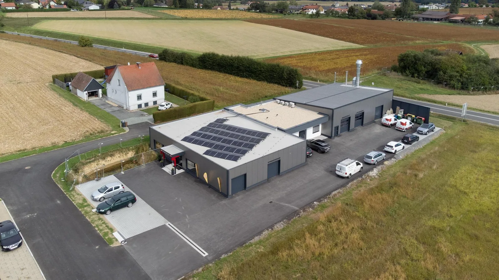 Gewerbehallen mit Flachdach und Photovoltaik aus der Luft, Felder ringsum
