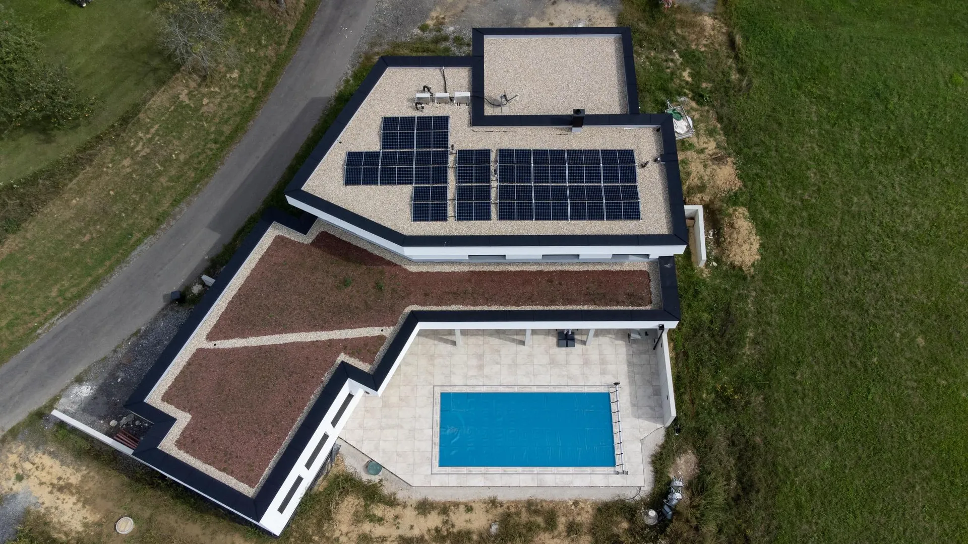 Einfamilienhaus von oben: Flachdach mit Kies und Photovoltaik, begrüntes Dach und Pool