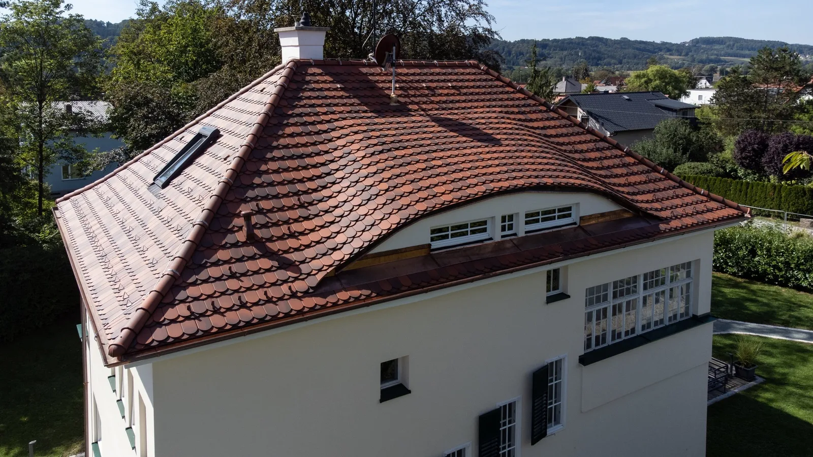 Villa mit rotbraunem Biberschwanz-Ziegeldach und geschwungener Gaube